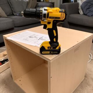 Drill on a half-built plywood cabinet with instructions