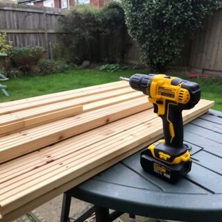 Drill outdoors with timber planks ready for a garden build